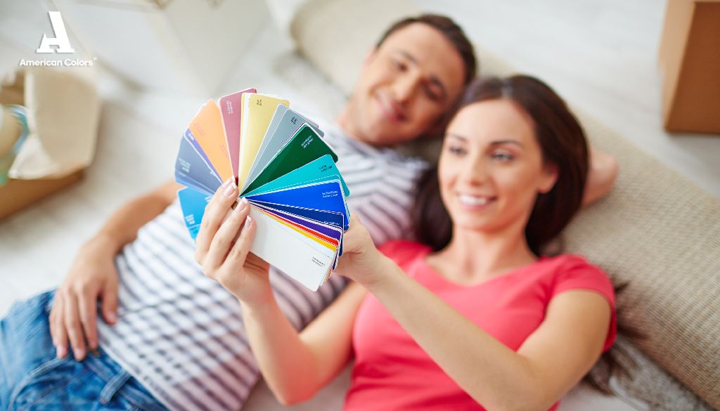 Pareja eligiendo entre colores de pintura para paredes interiores Pareja sonriente acostada en el suelo mirando una paleta de colores de pintura para paredes interiores